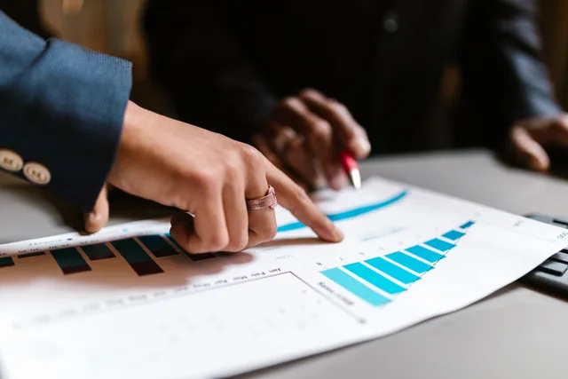 Close-up of hands analyzing financial charts during a business meeting. Recruitment marketing metrics every UK team should track